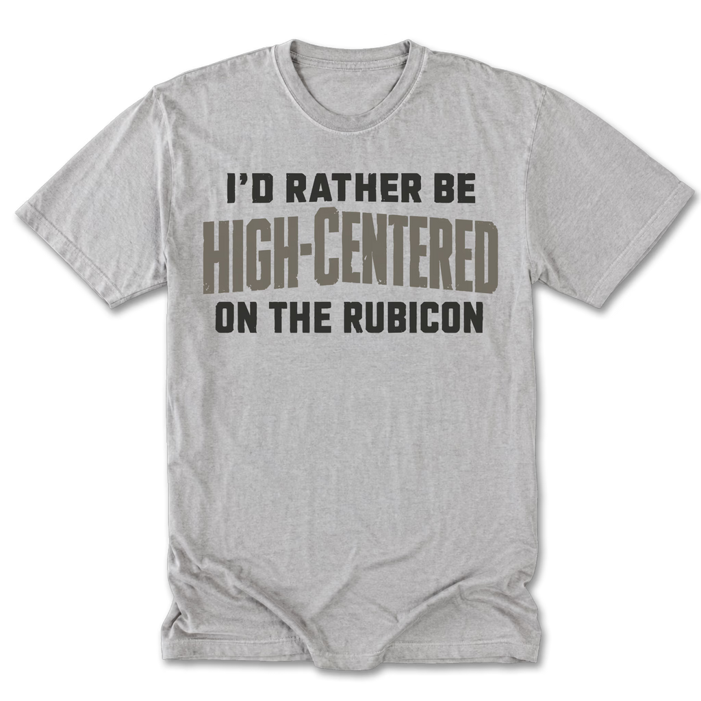 A light heather gray short-sleeve t-shirt with a humorous slogan printed on the front. The text reads 'I'D RATHER BE HIGH-CENTERED ON THE RUBICON' in black and brown block lettering.