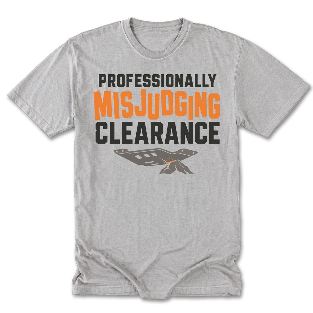 A light heather gray short-sleeve t-shirt with a graphic print on the front. The text reads 'PROFESSIONALLY MISJUDGING CLEARANCE' in black and orange lettering, with a small gray and orange ticket graphic below.