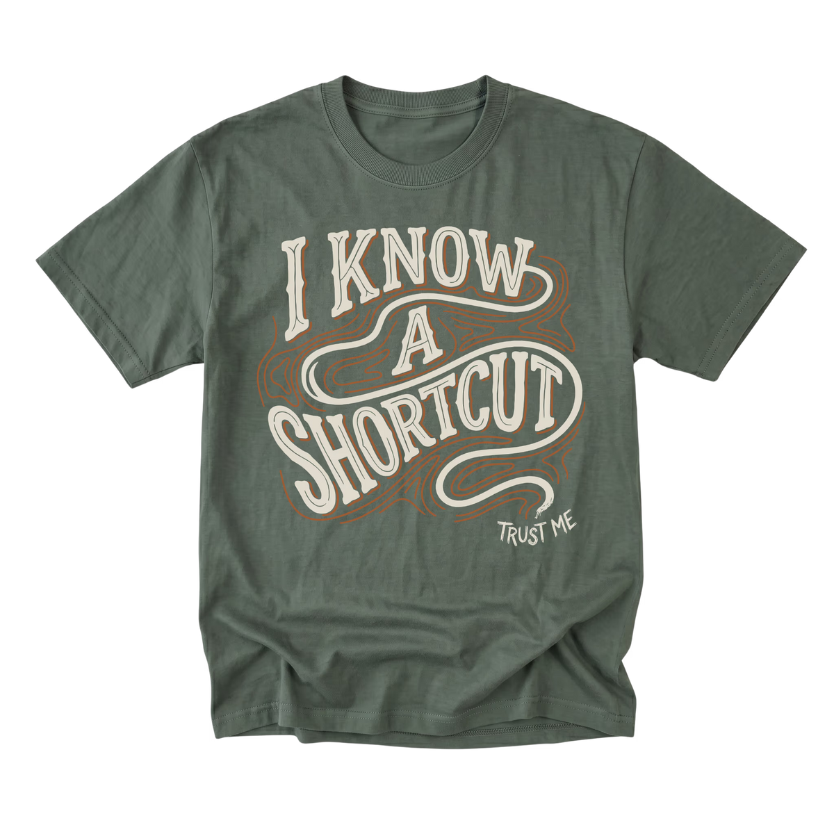An military green short-sleeve t-shirt with a vintage-style graphic reading 'I KNOW A SHORTCUT' in cream and brown, with 'TRUST ME' printed below in white.