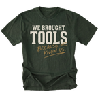 A moss green crewneck t-shirt with a graphic text print reading 'WE BROUGHT TOOLS BECAUSE WE KNOW US.' in cream and tan lettering, displayed on a clean white background.