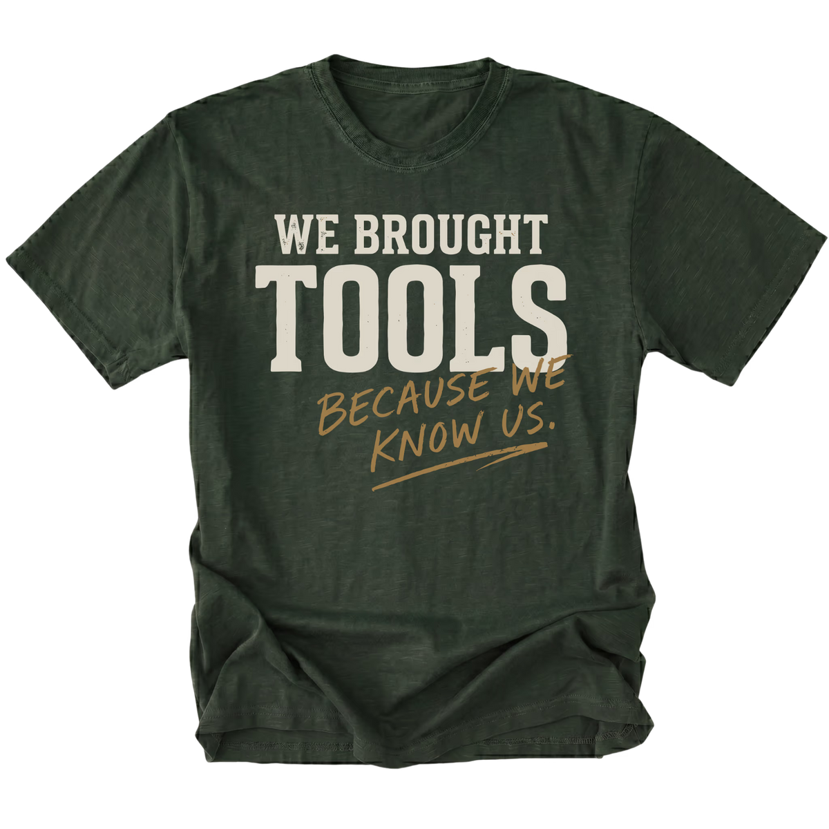 A moss green crewneck t-shirt with a graphic text print reading 'WE BROUGHT TOOLS BECAUSE WE KNOW US.' in cream and tan lettering, displayed on a clean white background.