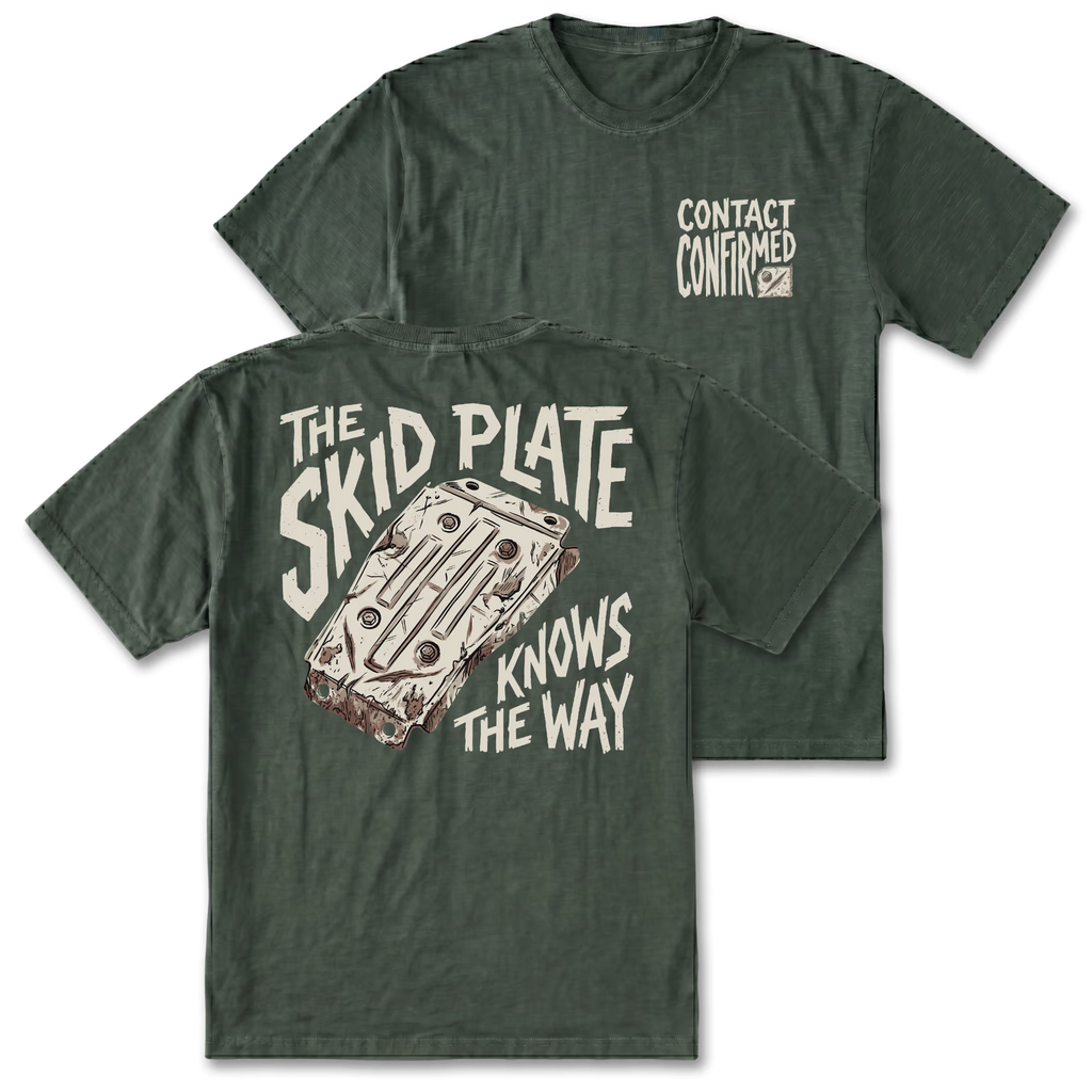 Two views of a dark green graphic t-shirt on a white background. The front view shows 'CONTACT CONFIRMED' printed on the left chest, while the back view features a large graphic of a rusty metal plate with the text 'THE SKID PLATE KNOWS THE WAY' in a distressed cream font.