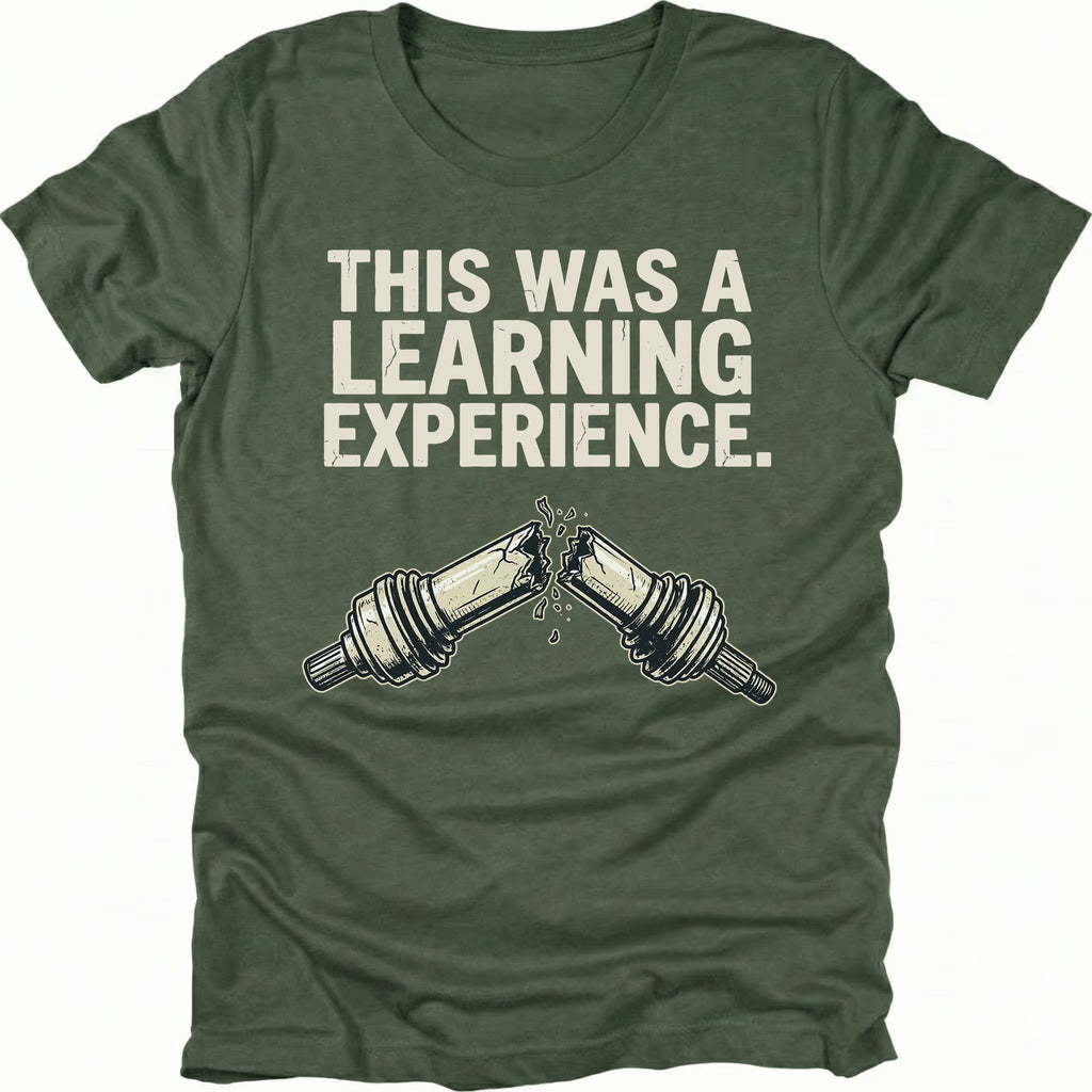 Moss t-shirt with text reading “This Was a Learning Experience” above an illustration of a broken axle or CV joint, shown on the front.