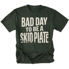 A moss green t-shirt with a distressed white graphic text that reads 'BAD DAY TO BE A SKID PLATE' on the front, displayed against a solid white background.