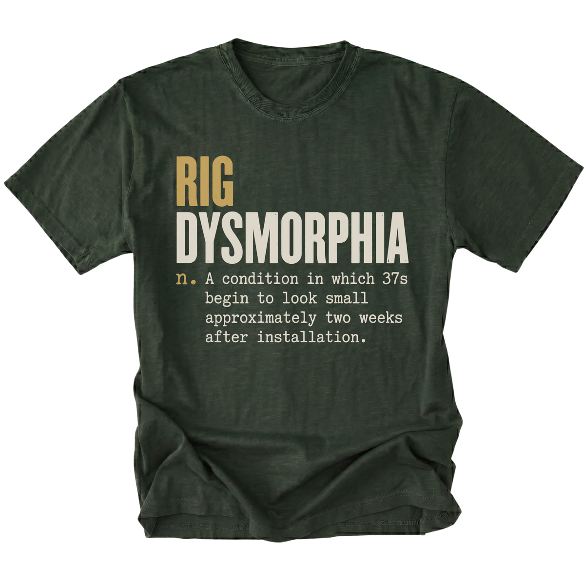 A moss green short-sleeve t-shirt with a humorous graphic print on the front. The text reads 'RIG DYSMORPHIA' in gold and white, followed by a definition in white typewriter font.
