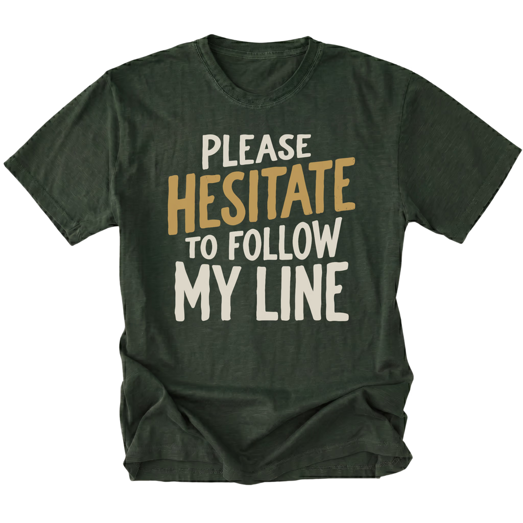 A moss green graphic t-shirt with the text 'PLEASE HESITATE TO FOLLOW MY LINE' printed on the front in white and mustard yellow, displayed against a solid white background.