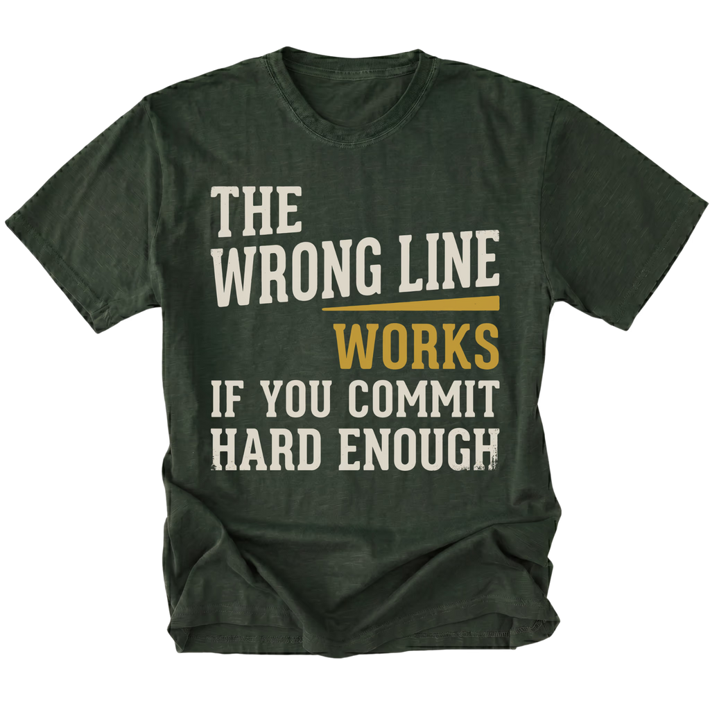 A moss green short-sleeve t-shirt with a distressed graphic text print that reads 'THE WRONG LINE WORKS IF YOU COMMIT HARD ENOUGH' in off-white and mustard yellow lettering, displayed on a solid white background.