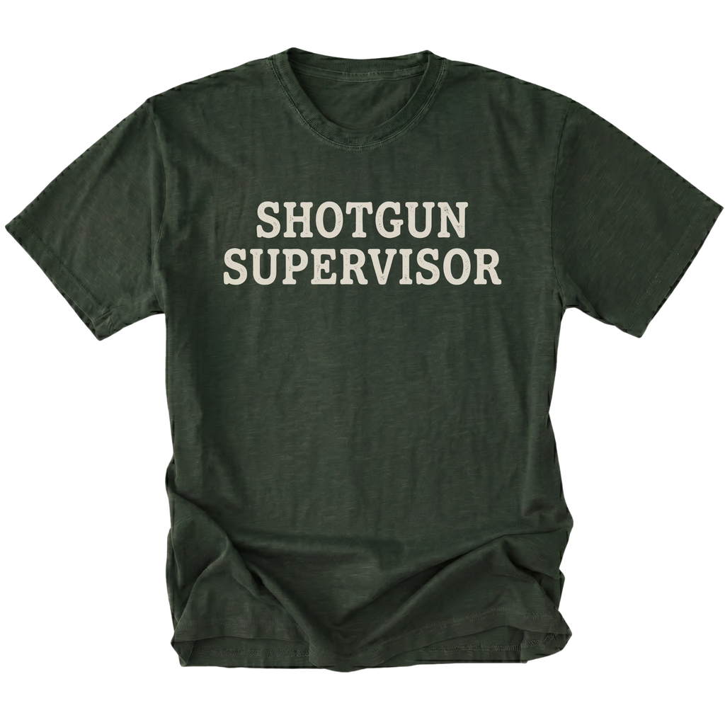 A moss green short-sleeve t-shirt with the words 'SHOTGUN SUPERVISOR' printed in a distressed cream-colored font across the chest, displayed on a solid white background.