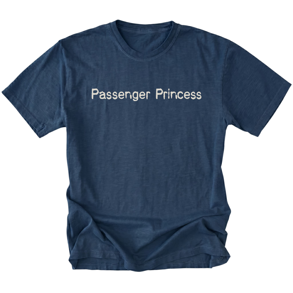 A navy blue short-sleeve t-shirt with the words 'Passenger Princess' printed in a light beige serif font across the chest, displayed against a solid white background.