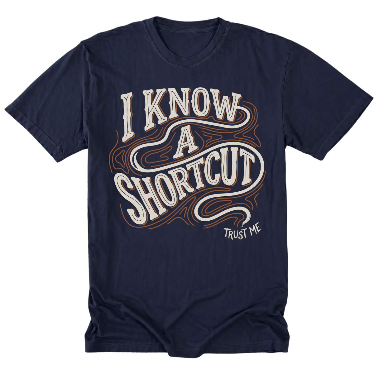 A navy blue short-sleeve t-shirt with a graphic on the front that reads 'I KNOW A SHORTCUT' in white and orange wavy lettering, with 'TRUST ME' written below in white.
