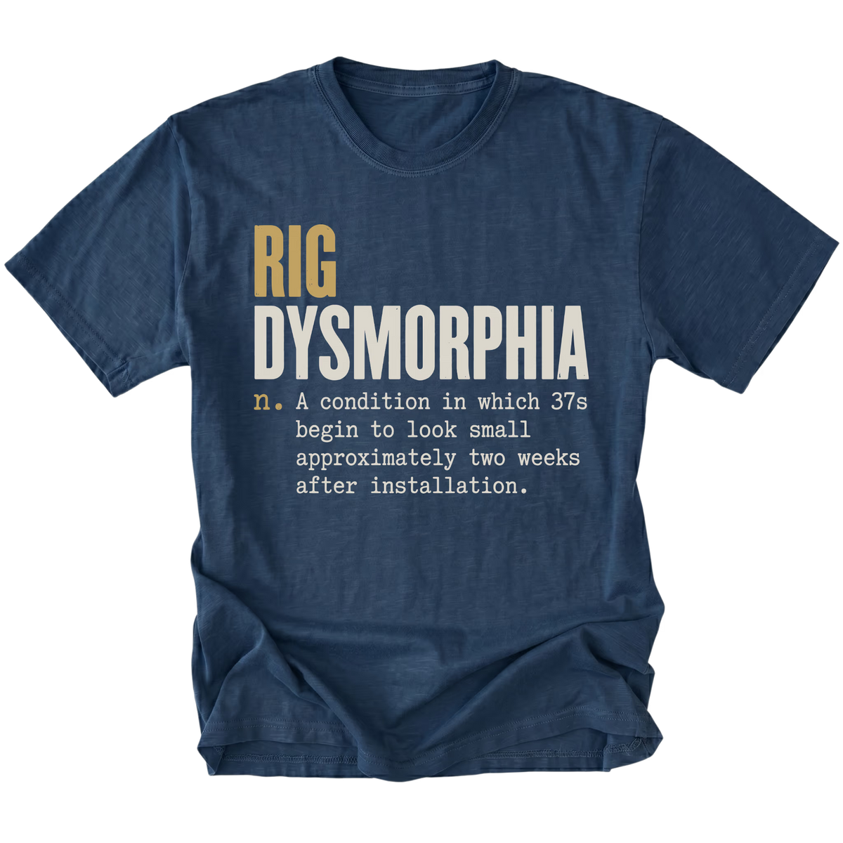 A navy blue short-sleeve t-shirt with a humorous graphic print on the front. The text reads 'RIG DYSMORPHIA' in gold and white, followed by a definition in white typewriter font.