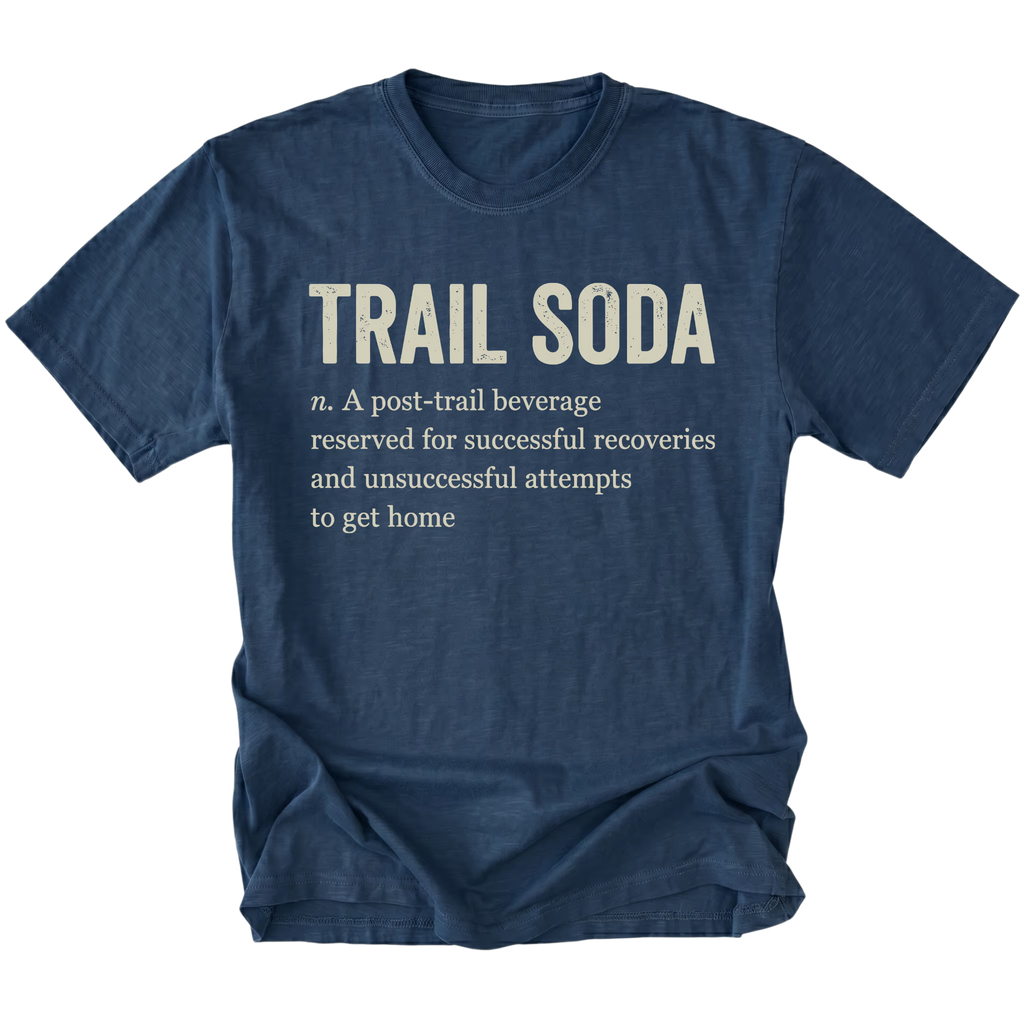 A navy blue short-sleeve t-shirt with a humorous dictionary-style definition printed on the front chest reading 'TRAIL SODA' and a smaller definition below, shown on a plain white background.