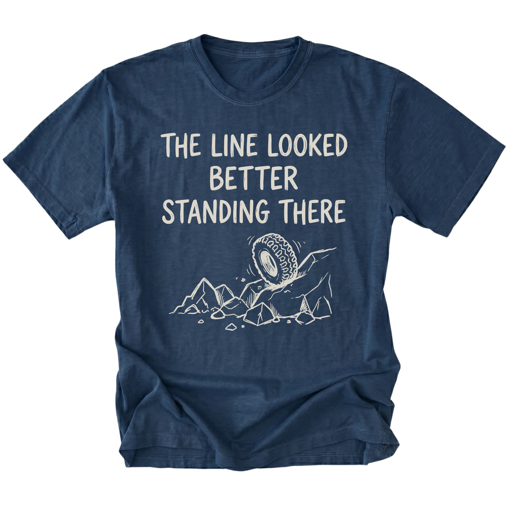 Navy T-Shirt with hand-drawn tire and rocks graphic and text reading “The Line Looked Better Standing There” shown on front view by Trail Snark.