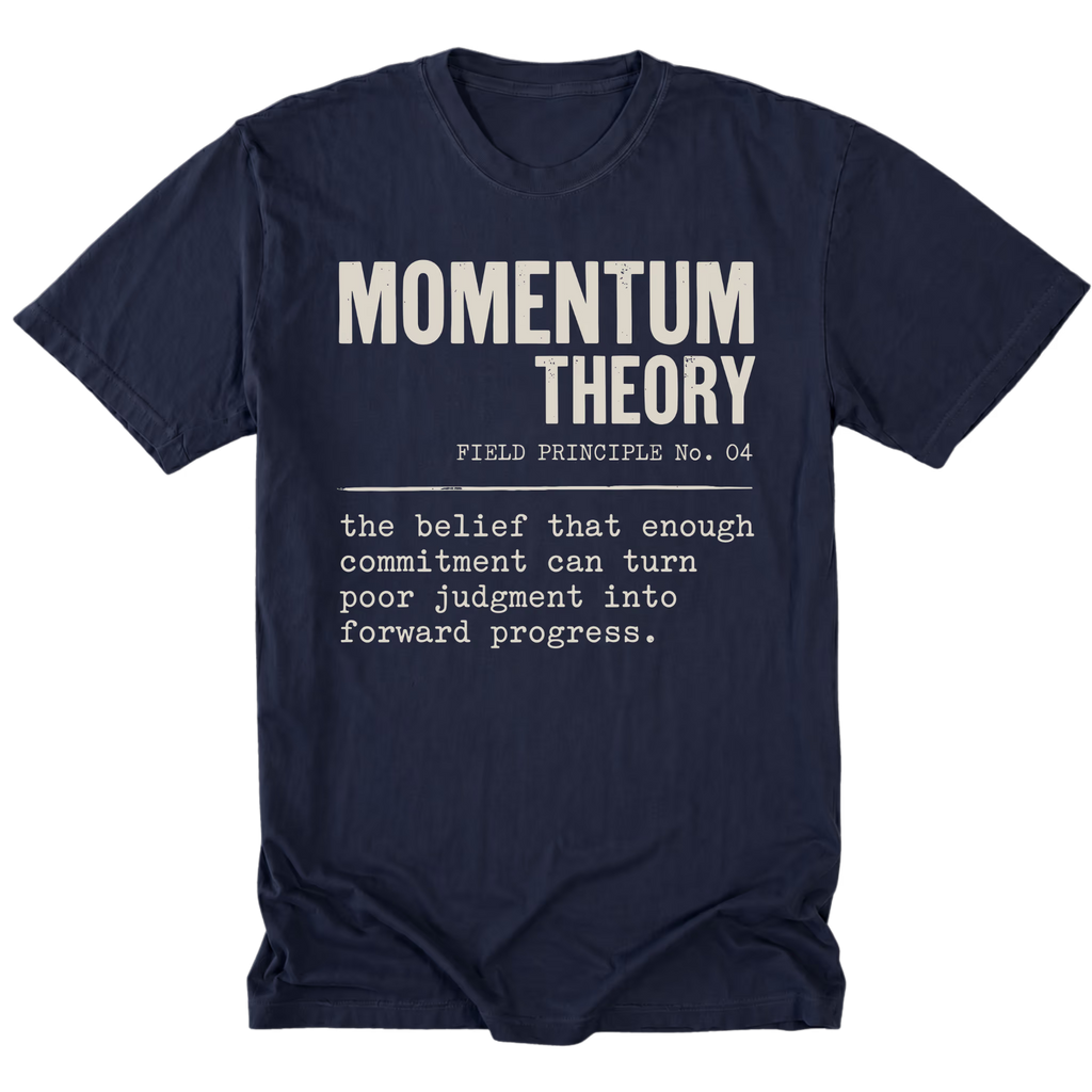 A navy blue short-sleeve t-shirt with a white typewriter-style graphic on the front reading 'MOMENTUM THEORY' and a quote below, shown on a plain white background.