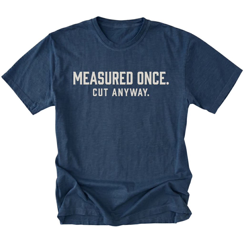 Navy t-shirt with white text reading Measured Once. Cut Anyway., front view.