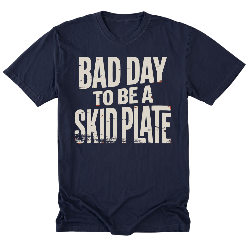 A navy blue tall short-sleeve t-shirt with a distressed white graphic text reading 'BAD DAY TO BE A SKID PLATE' on the front, displayed against a solid white background.