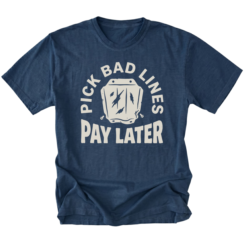 A navy blue short-sleeve t-shirt with a distressed white graphic on the front that reads 'PICK BAD LINES PAY LATER' around a coffin icon, shown on a plain white background.