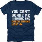 Navy t-shirt with bold distressed text reading “You Can’t Scare Me I Ignore the Check Engine Light” with an orange check engine icon on the front.