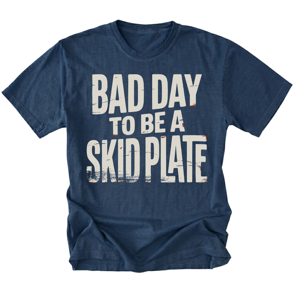 A navy blue short-sleeve t-shirt with a distressed white graphic print that reads 'BAD DAY TO BE A SKID PLATE' on the front, displayed against a solid white background.