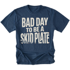 A navy blue short-sleeve t-shirt with a distressed white graphic print that reads 'BAD DAY TO BE A SKID PLATE' on the front, displayed against a solid white background.